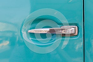 Close-up shiny steel car door handle retro style on turquoise ca