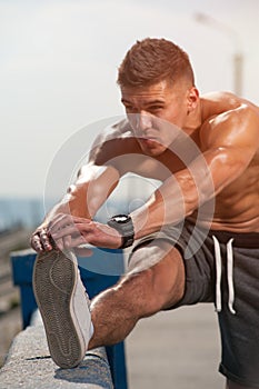 Close-up shirtless young male jogger warmimg up