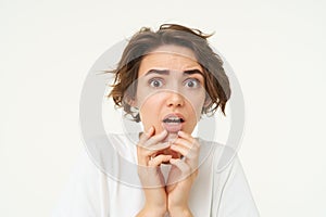 Close up of shocked, concerned woman, gasps in fear, looks scared and startled, stands over white studio background