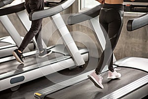 Close up shoe group of young  people walking on treadmills warm up in sport gym  . two fitness woman runner on running machine in