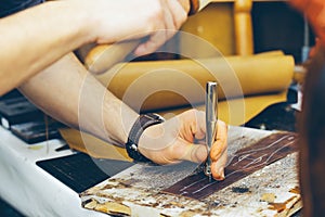 Close up of a shoemaker or artisan worker hands. Leather craft tools on old wood table