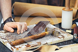 Close up of a shoemaker or artisan worker hands. Leather craft tools on old wood table