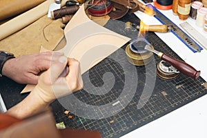 Close up of a shoemaker or artisan worker hands. Leather craft tools on old wood table