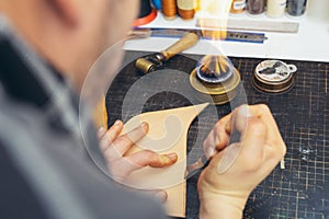 Close up of a shoemaker or artisan worker hands. Leather craft tools on old wood table