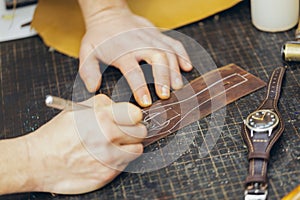 Close up of a shoemaker or artisan worker hands. Leather craft tools on old wood table