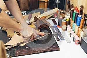 Close up of a shoemaker or artisan worker hands. Leather craft tools on old wood table