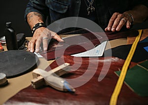 Close up of a shoemaker working with leather textile and hammer at a workshop