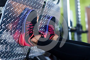 Close up shoes of a fit young woman doing leg press in the gym
