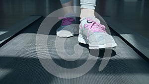 Close-up on the shoes of a woman running on the treadmill at the gym