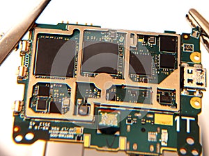 Close up shoot of printed circuit board PCB sitting on a white repair stand with magnifier for better examining small parts