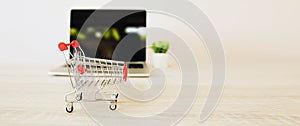 Close up the shopping cart with laptop or tablet at desk concept using the internet application for online shopping buying and spe