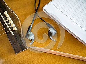 Close up shot of acoustic guitar with earphone