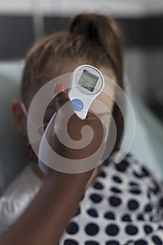 Close up shot of african american nurse measuring sick little girl body temperature
