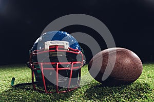 close-up shot of american football helmet with ball on green grass