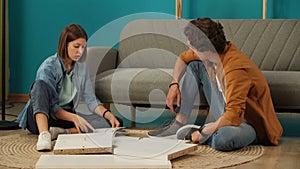 Close up shot of apartment living room. Man and woman assembling new furniture, woman reading instructions to man.