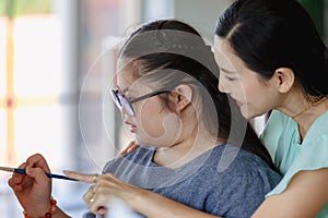 Close up shot of Asian happy lovely mother face standing smiling encouraging young chubby down syndrome autistic autism little