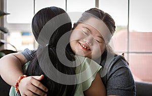 Close up shot of Asian happy lovely young chubby down syndrome autistic autism little daughter smiling hugging cuddling embracing