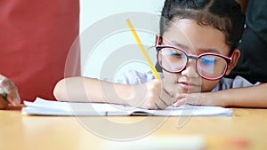 Close up shot Asian little girl doing homework and her mother teach