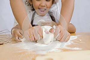 Close up shot of Asian little girl with hands of mother kneading