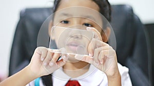 Close up shot Asian little girl in Thai kindergarten student uniform using clear glass same like smart phone for futuristic cyber