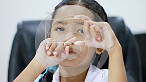 Close up shot Asian little girl in Thai kindergarten student uniform using cleas glass same like smart phone for futuristic cyber