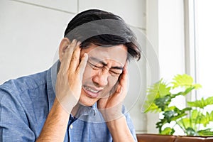 Close up shot of Asian male  senior using hands to touch his head when suffering and pain from headache. Health problem or stress
