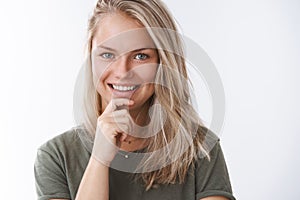 Close-up shot of attractive confident and positive european blonde with small tattoo touching chin assured smiling