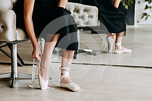 Close-up shot of a ballerina taking off the ballet shoes sitting on the floor in the studio