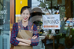 Close-up shot of a beautiful Asian coffee shop owner. small family job and the employment sign was affixed to the glass door.