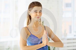 Close up shot of beautiful European girl holding hands in namaste in front of her while meditating alone early in the morning.