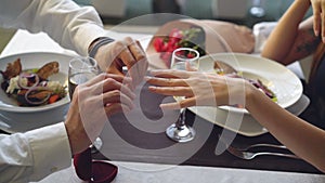 Close-up shot of beautiful ring being placed on female finger during marriage proposal at romantic dinner in restaurant
