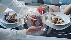 Close-up shot of beautiful ring being placed on female finger during marriage proposal at romantic dinner in restaurant