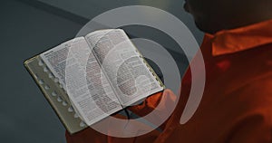 Close up shot of Bible. African American prisoner holds book in hand