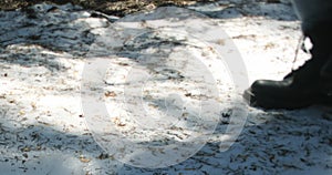 Close-up shot of black boots of a person walking on freshly fallen snow.