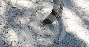 Close-up shot of black boots of a person walking on freshly fallen snow.