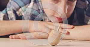 Close up shot of a boy spinning a Hanukka dreidel on the floor