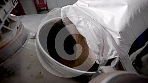 Close-up shot of a brewer pouring fresh wheat barley in a vessel in a brewhouse.