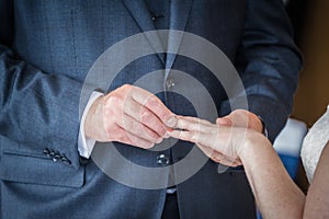 Close up shot of bride holding out hand as groom at wedding ceremony placing ring on finger whilst saying vows and I do to seal th