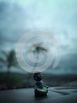 Close-up shot of a Buddha statue, placed on the dashboard of a car