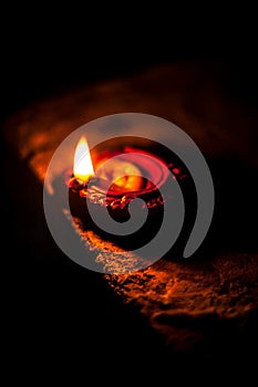 Close-up shot of burning Diva or divida or Diya or oil lamp isolated in dark.