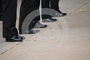 Close-up shot of a business man wearing slacks and black leather shoes standing on a cement floor, outdoor street, optional focus.