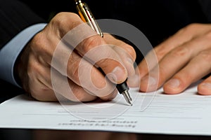 Close up shot of a businessman signing a business contract. Businessman writing on a paper document