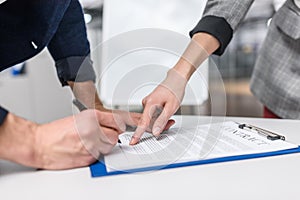 close-up shot of businessman signing contract while manageress pointing