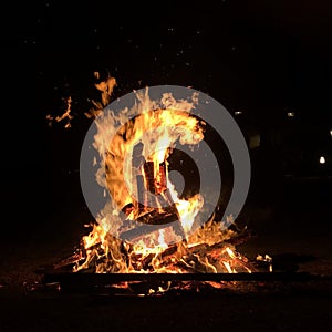 Close-up shot of a campfire with flames and smoke at a campsite at night