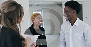 Close-up shot captures the moment as the blonde woman real estate agent hands the key to the African couple, their faces