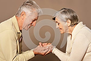 Close up shot of a cheerful senior couple at home holding hands