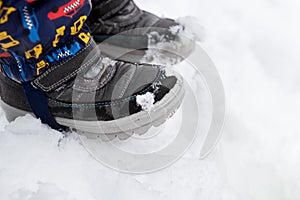 Close up shot of childrens snow boots. Winter footware. Boy standing in snow, shoes detail.