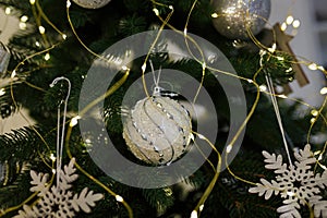 Close up shot of Christmas tree branch with bauble and wooden toys. Beautiful garland lights boke on background