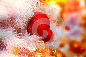 Close-up shot of Christmastide decoration with red balls and white fir tree on golden lighting bokeh background. photo