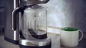 Close-up shot of coffee brewing in coffee maker and flowing in to carafe